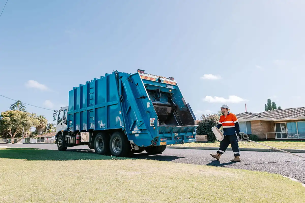 Blue waste truck collecting items off the verge 